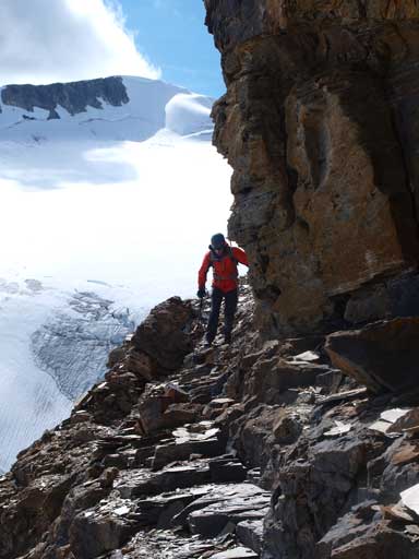 Mike traversing beneath a vertical cliff band. Mt. McArthur behind.