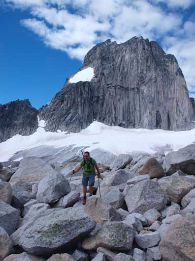 Eric hiking through a boulder field, with Snowpatch Spire behind