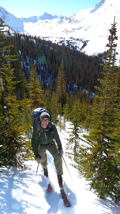 Eric skinning up a steep treed slope