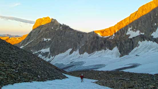 Ben hiking up a small snow patch, with more morning colours behind