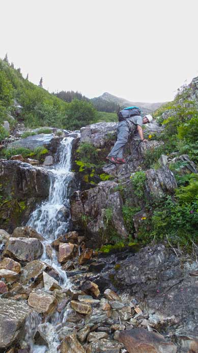 Eric down-climbing slippery terrain beside a mini waterfall