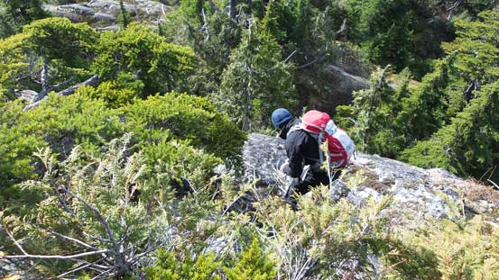 Simon down-climbing the crux using a rope as hand-line