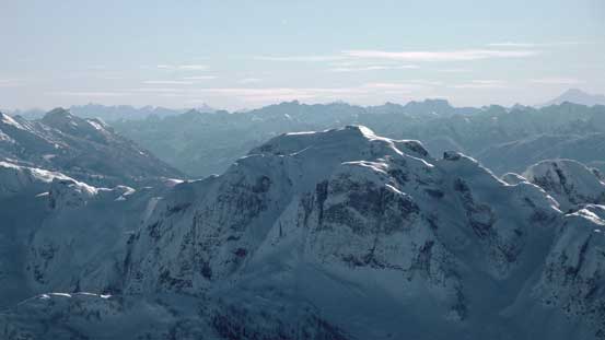 In the foreground is Snow Pillow Peak. Behind on the skyline Slesse, Clarke and Baker are visible