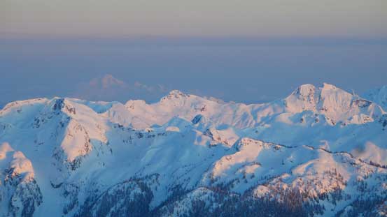 Evening alpenglow on peaks by Watersprite Lake, with the faint outline of Mt. Baker behind